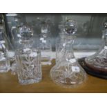 A CUT GLASS SHIP?S DECANTER; TWO SQUARE SPIRIT DECANTERS; CUT GLASS WINE DECANTER WITH LARGE