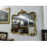 A CARTOUCHE SHAPED WALL MIRROR IN GILT FRAME
