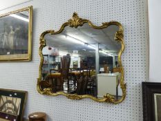 A CARTOUCHE SHAPED WALL MIRROR IN GILT FRAME