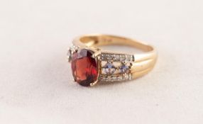 9ct GOLD RING set with an oval wine red topaz, the shoulders each set with two diamond shaped