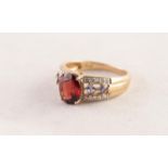 9ct GOLD RING set with an oval wine red topaz, the shoulders each set with two diamond shaped