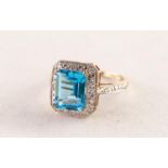 9ct WHITE GOLD RING set with an emerald cut blue topaz above a surround of eight tiny diamonds, 3