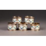 GEORGE V SET OF FIVE SILVER AND GUILLOCHE ENAMELLED NAPKIN RINGS, each painted with floral swags