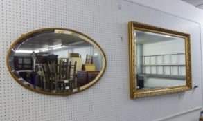 AN OBLONG BEVELLED EDGE WALL MIRROR, IN GILT FOLIATE SCROLL EMBOSSED FRAME, 3?4? WIDE AND AN OVAL