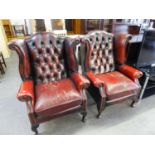 A PAIR OF TWENTIETH CENTURY LEATHER COVERED WINGED BACK ARMCHAIRS (SHOWING WEAR)