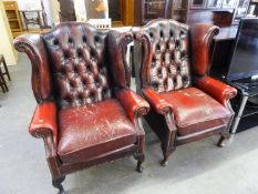 A PAIR OF TWENTIETH CENTURY LEATHER COVERED WINGED BACK ARMCHAIRS (SHOWING WEAR)