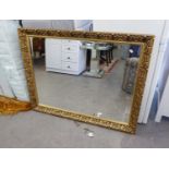 A LARGE OBLONG BEVELLED EDGE WALL MIRROR, IN FOLIATE EMBOSSED GILT FRAME, 3' x 3'9"