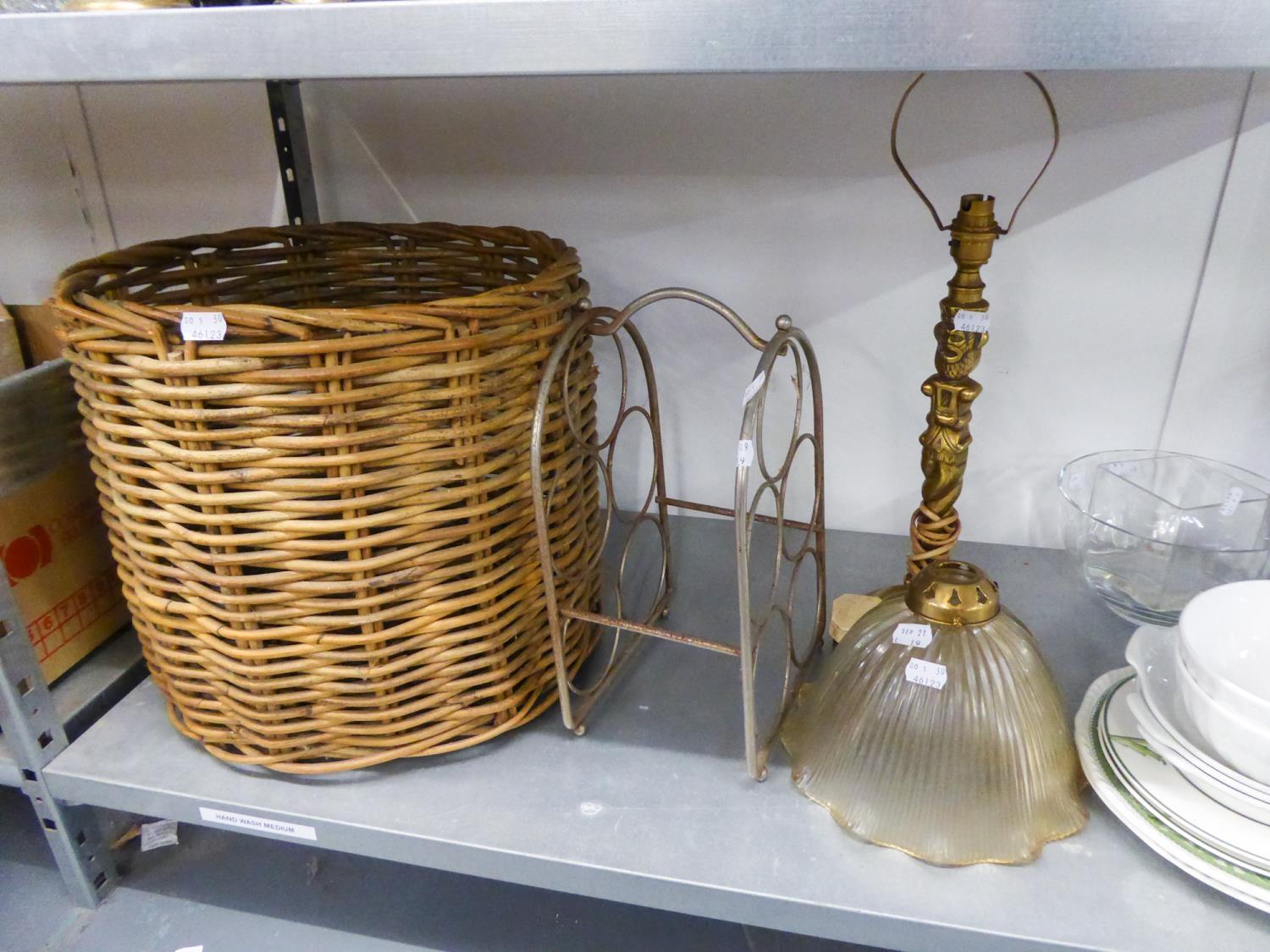 A METAL FIVE BOTTLE WINE RACK;  A WICKER LOG BASKET; A HEAVY BRASS TOTEM PATTERN TABLE LAMP AND