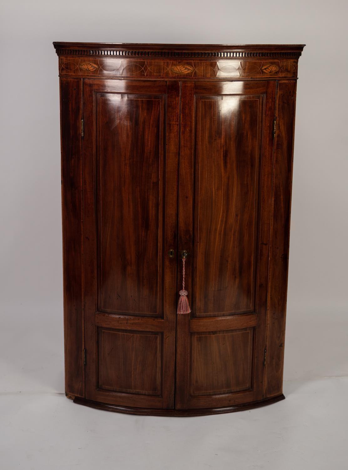 NINETEENTH CENTURY INLAID MAHOGANY BOW FRONTED CORNER CUPBOARD, the dentil moulded cornice above a