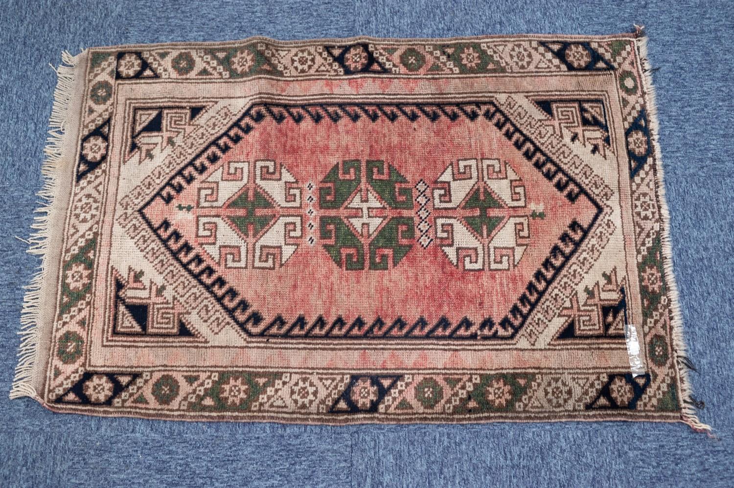 KARADAGH RUG, with row of three latch hook pattern medallions on a faded red field with spandrels,