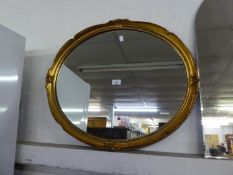 AN OVAL WALL MIRROR IN SWEPT GILT FRAME