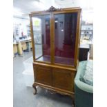 A CARVED AND FIGURED WALNUT DISPLAY CABINET, THE UPPER PORTION WITH TWO GLAZED DOORS AND GLAZED