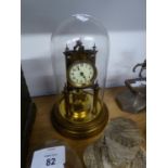 A BRASS ANNIVERSARY CLOCK UNDER GLASS DOME SHADE