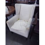 AN EDWARDIAN WINGED EASY ARMCHAIR, COVERED IN OFF-WHITE SQUARE PATTERNED EMBOSSED FABRIC, ON
