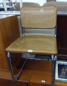 A BRIGHT METAL TUBULAR FRAMED CANTILEVER CHAIR WITH CANE PANEL BACK AND SEAT