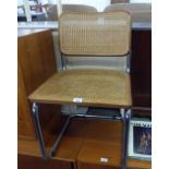 A BRIGHT METAL TUBULAR FRAMED CANTILEVER CHAIR WITH CANE PANEL BACK AND SEAT
