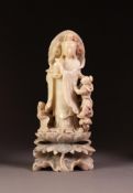 CHINESE CARVED SOAPSTONE GROUP, modelled as Guan-Yin holding an urn with a child at her side, raised