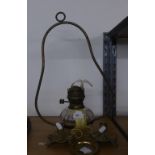 A CEILING SUSPENDED OIL LAMP WITH GLASS RESERVOIR, TWO BRASS CANDLE HOLDERS AND A SMALL BRASS
