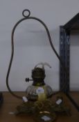 A CEILING SUSPENDED OIL LAMP WITH GLASS RESERVOIR, TWO BRASS CANDLE HOLDERS AND A SMALL BRASS