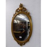 A GILT FRAMED OVAL WALL MIRROR