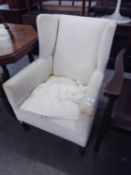 AN EDWARDIAN WINGED EASY ARMCHAIR, COVERED IN OFF-WHITE SQUARE PATTERNED EMBOSSED FABRIC, ON