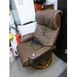 AN ELECTRONIC MODERN REVOLVING EASY ARMCHAIR, COVERED IN BROWN HIDE AND THE MATCHING STOOL