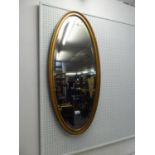 A NARROW OVAL BEVELLED EDGE WALL MIRROR, IN GILT FRAME (102cm high x 45cm wide)