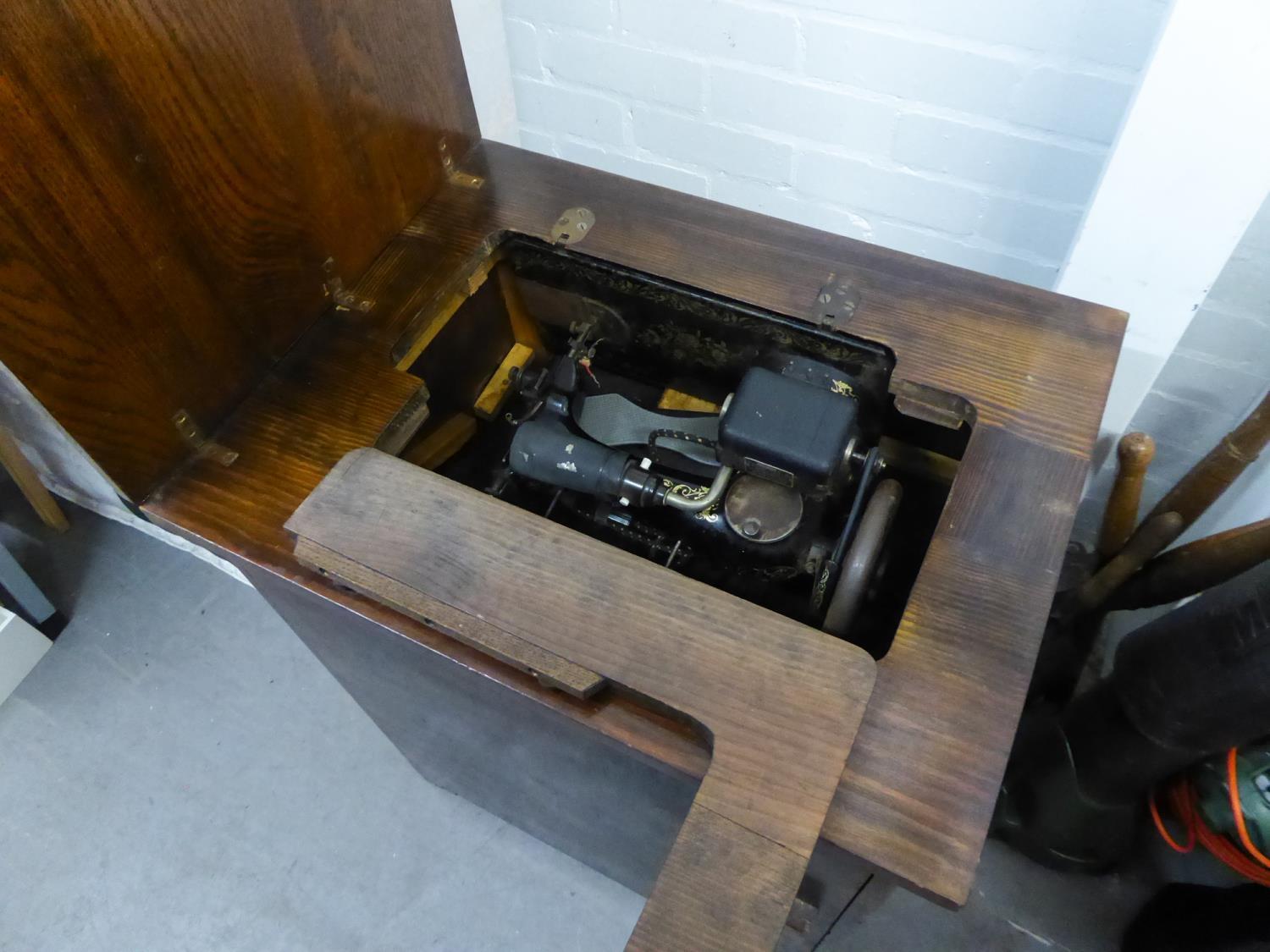 A VINTAGE SINGER DROP-HEAD ELECTRIC SEWING MACHINE WITH FOOT CONTROL, IN OAK CASE WITH CUPBOARD BASE