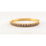 GOLD COLOURED METAL, FOLIATE SCROLL CHASED, HINGE OPENING BANGLE, the pierced half-hoop top set with