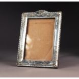 EDWARD VII EMBOSSED SILVER FRONTED DESK TOP PHOTOGRAPH FRAME, of oblong form with ribbon tied bell