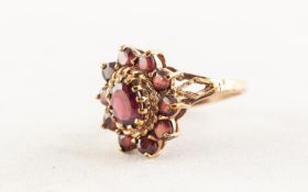 9ct GOLD AND GARNET OVAL CLUSTER RING set with a centre oval garnet and surround of ten small
