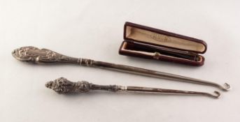 TWO STEEL BUTTON HOOKS with embossed silver handles and an amber coloured CIGARETTE HOLDER