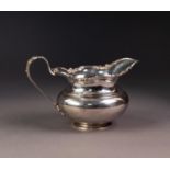 GEORGE V SILVER MILK JUG, of bellied, footed form with floral cast and pierced border, conforming