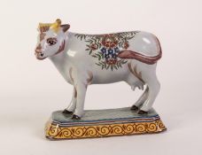 PROBABLY 19th CENTURY DUTCH POLYCHROME DELFT MODEL OF A COW standing on a canted oblong spreading