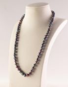 SINGLE STRAND NECKLACE OF 65 UNIFORM BLACK CULTURED PEARLS, with twelve paste set spacers and silver