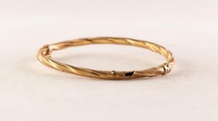 9ct GOLD HINGE OPENING HOLLOW BANGLE of spirally twisted and engraved form, 4.2 gms