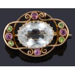 A delicate Edwardian pink and green gem stone set scroll brooch