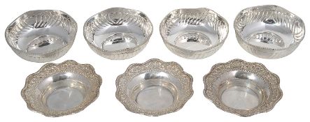 A set of four foreign white metal bowls together with a set of three white metal dishes