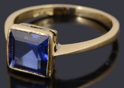 A delicate single stone square shaped step cut synthetic sapphire ring,