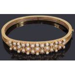 A decorative late Victorian gold seed pearl hinge bangle