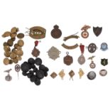 A collection of military buttons, fobs and cap badges
