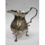 Early hallmarked silver repousse decorated cream jug, with repousse decoration, on raised