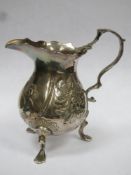 Early hallmarked silver repousse decorated cream jug, with repousse decoration, on raised