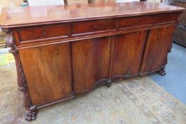 19th century mahogany four door, four drawer, with heavily carved decoration, on raised claw