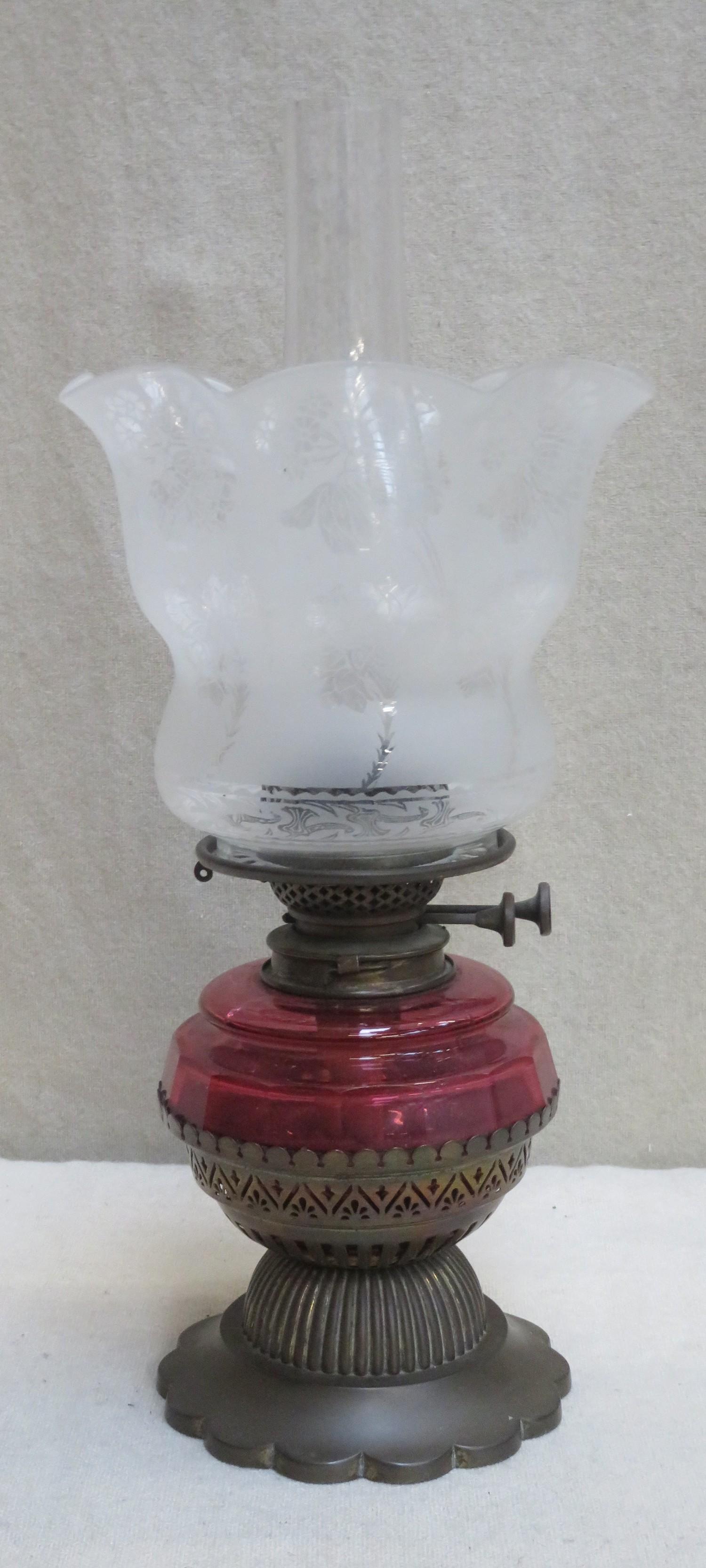 Victorian brass piercework decorated shallow oil lamp, with cranberry glass reservoir and floral