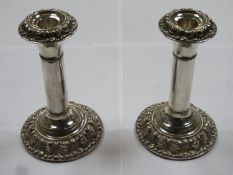 Pair of hallmarked silver candlesticks, with repoussé foliate banded decoration to top and base,