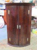 19th century mahogany bow fronted wall mounted corner cupboard, fitted with three drawers inside.