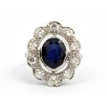 An 18ct white gold (stamped 18k) cluster ring set with an oval cut sapphire surrounded by