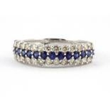 An 18ct white gold (stamped 750) half eternity ring set with a row of round cut sapphires flanked by