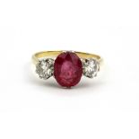 An 18ct yellow gold ring set with an oval cut ruby flanked by brilliant cut diamonds, approx. 0.90ct